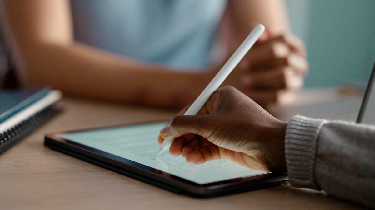 Eine Hand schreibt mit einem Stift auf einem Tablet. 