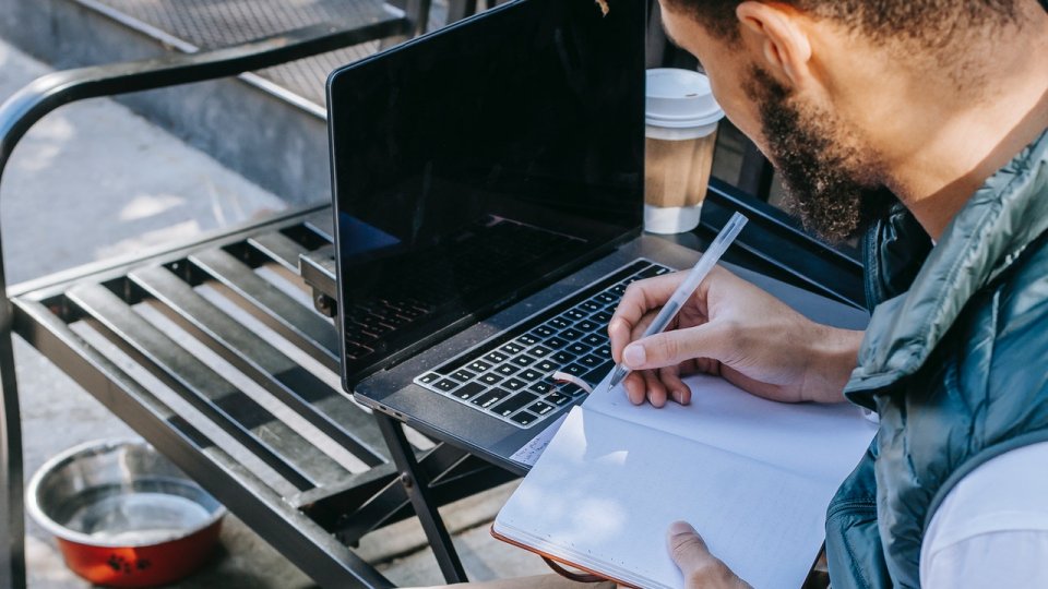 Foto eines Mannes, der in einem Café mit Laptop arbeitet