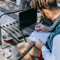 Foto eines Mannes, der in einem Café mit Laptop arbeitet