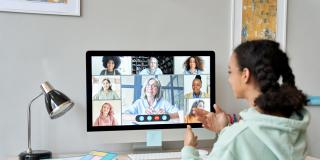 Junge Frau vor einem Bildschirm während eines Online Meetings.